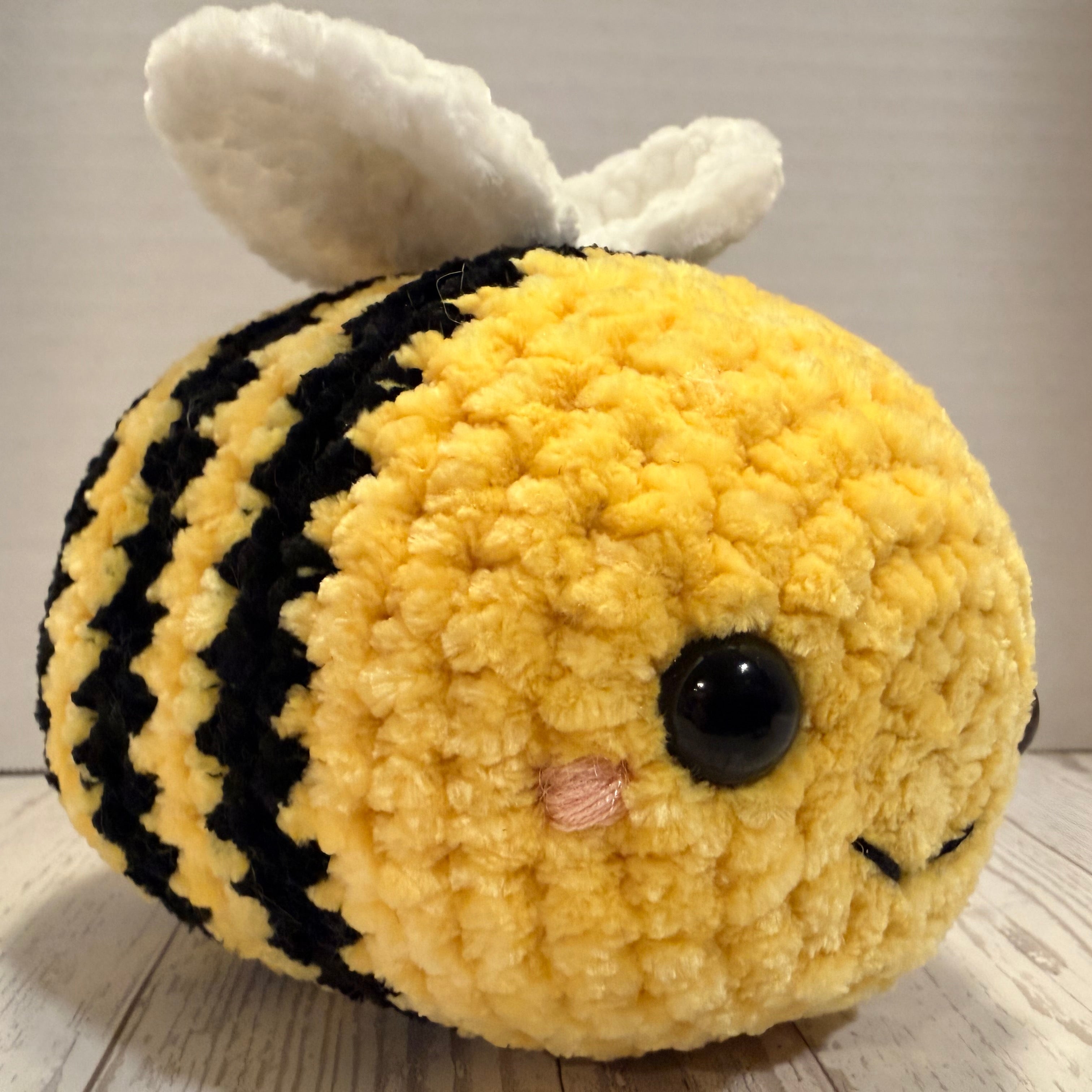 Plush toy bee with black stripes on a wooden surface