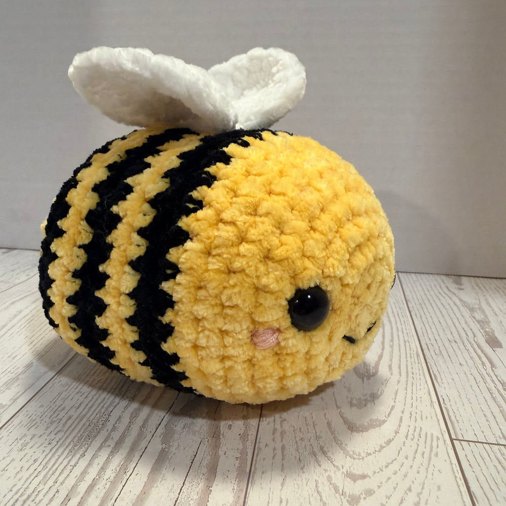 Crocheted bee plush toy on a wooden surface