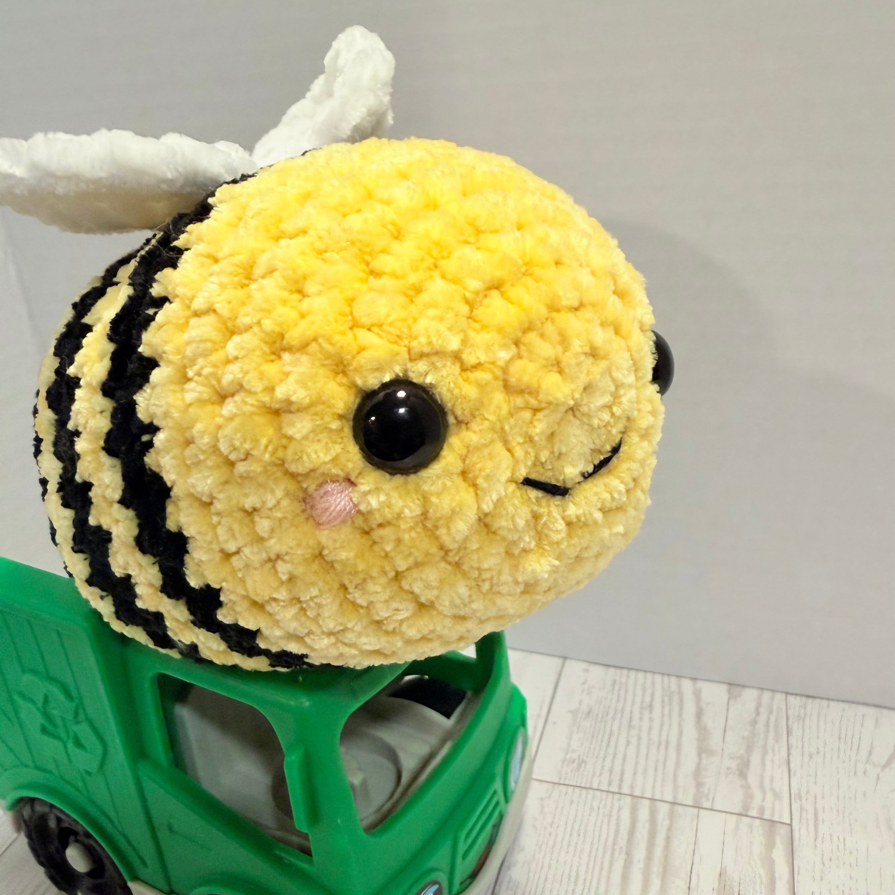 Plush bee toy on a green toy truck with a plain background